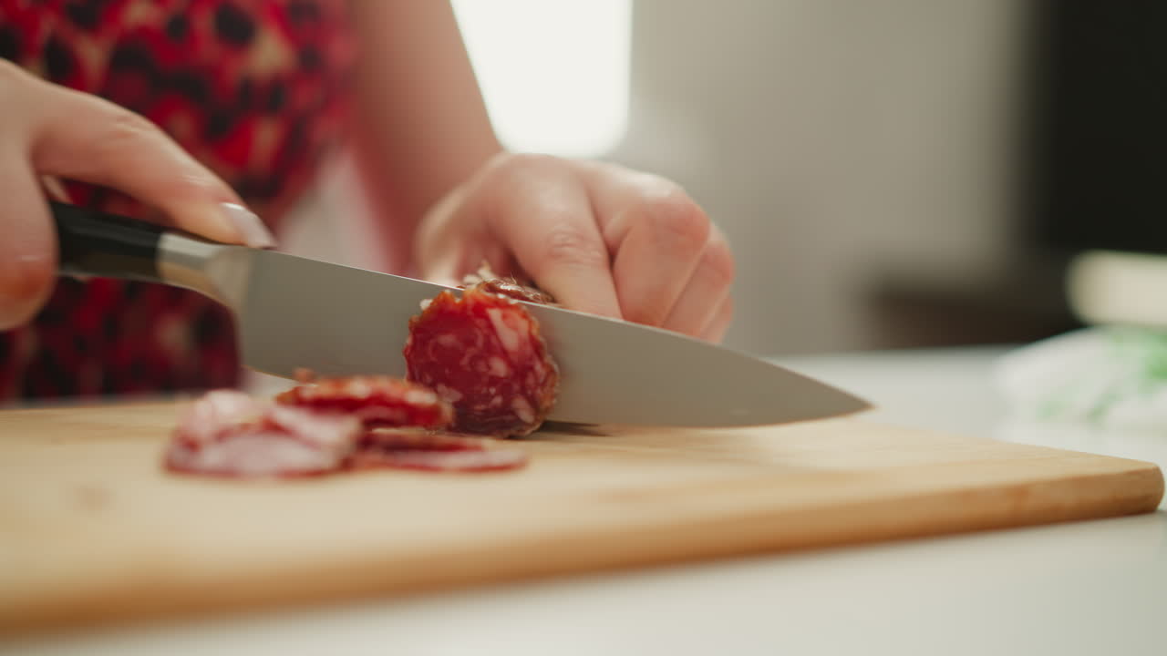 Woman slicing sausage on a wooden cutting board