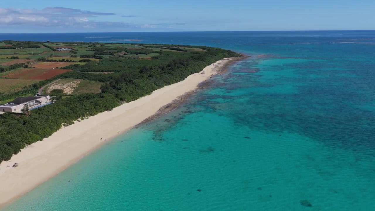Riprese aeree orizzontali che scendono a sinistra sopra la costa di sabbia bianca e le acque turchesi di Musunun Beach sull'isola di Kurima, Miyakojima, Okinawa, Giappone