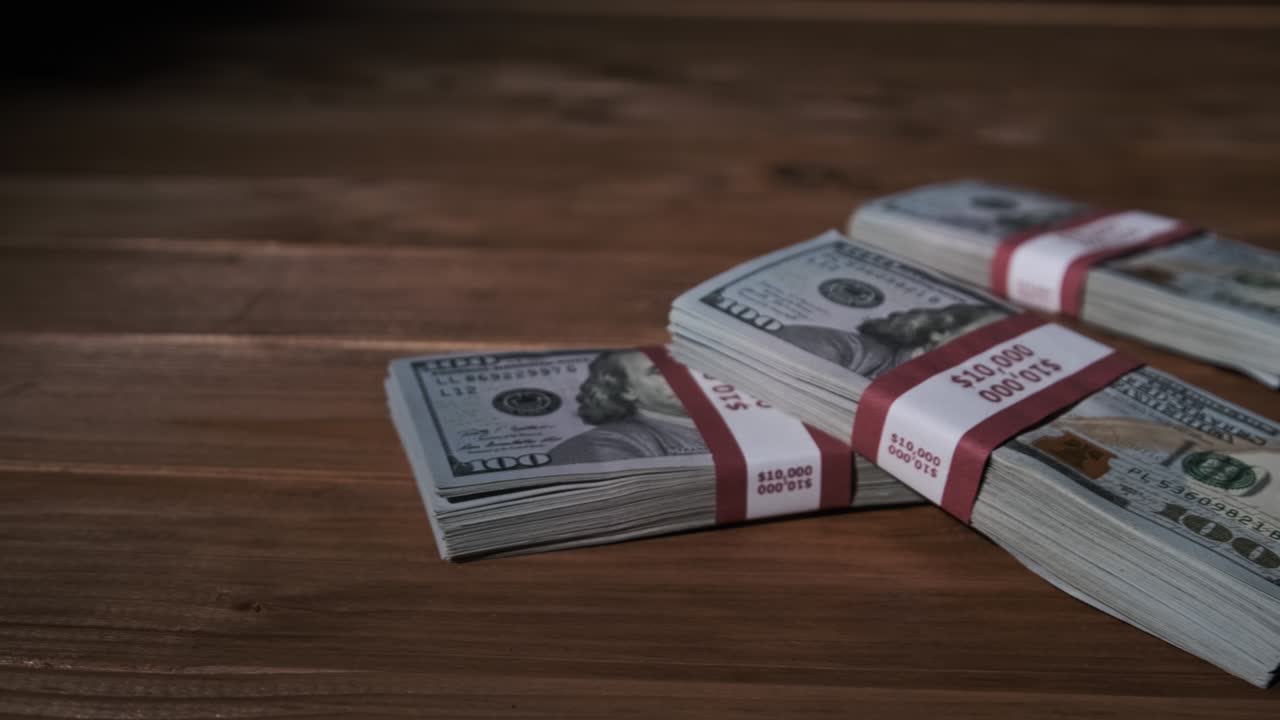 tres pilas de 10.000 dólares estadounidenses billetes en paquetes se encuentran en la mesa de madera