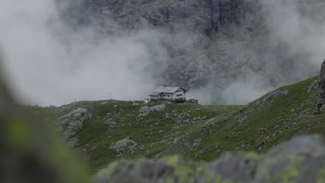 building seen in background in valmalenco mountains with rising foggy clouds