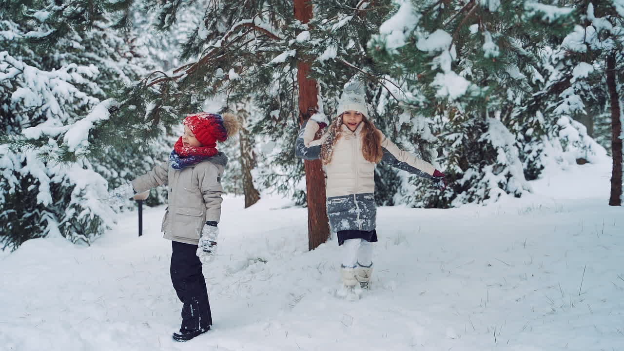 Child at winter in nature. Happy kids playing together with snow, outdoors winter vacation
