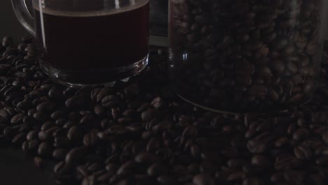 a close-up shot of coffee beans into a reveal of a glass cup and container.