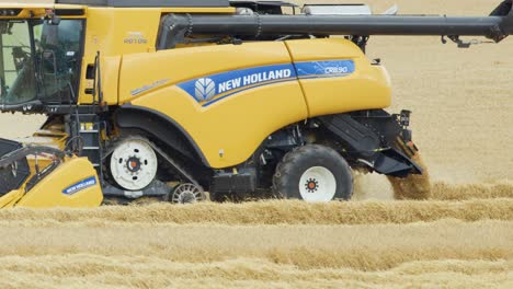a large yellow combine harvester moves steadily through a golden wheat field under daylight, efficiently gathering crops in a rural agricultural landscape
