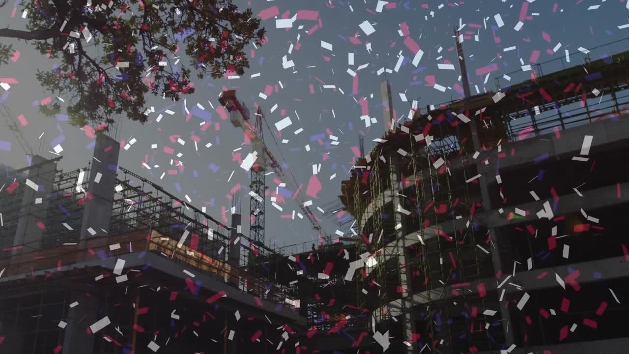 クレーンがある建設現場に、上空から突然放出された紙吹雪が祝祭的なシャワーを降らせる。