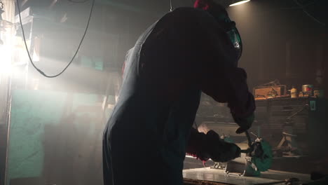 Worker-with-visor-sharpens-tool-on-bench-grinder