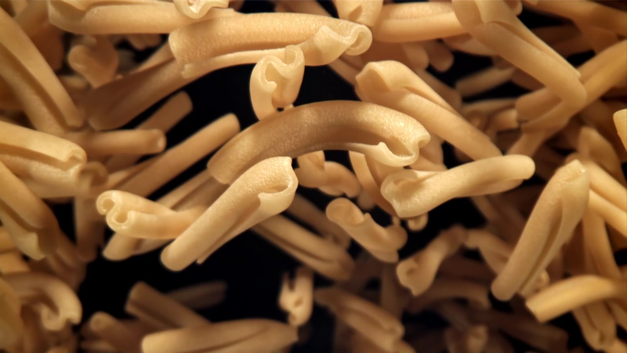Primo piano al rallentatore di pasta secca che cade a fuoco