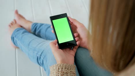 mujer usando un teléfono inteligente con pantalla verde