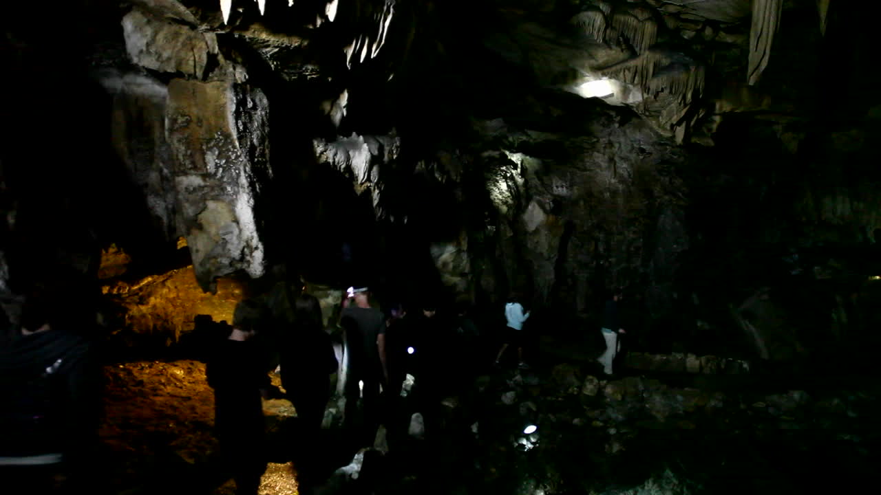 People explore a dark cave with flashlights