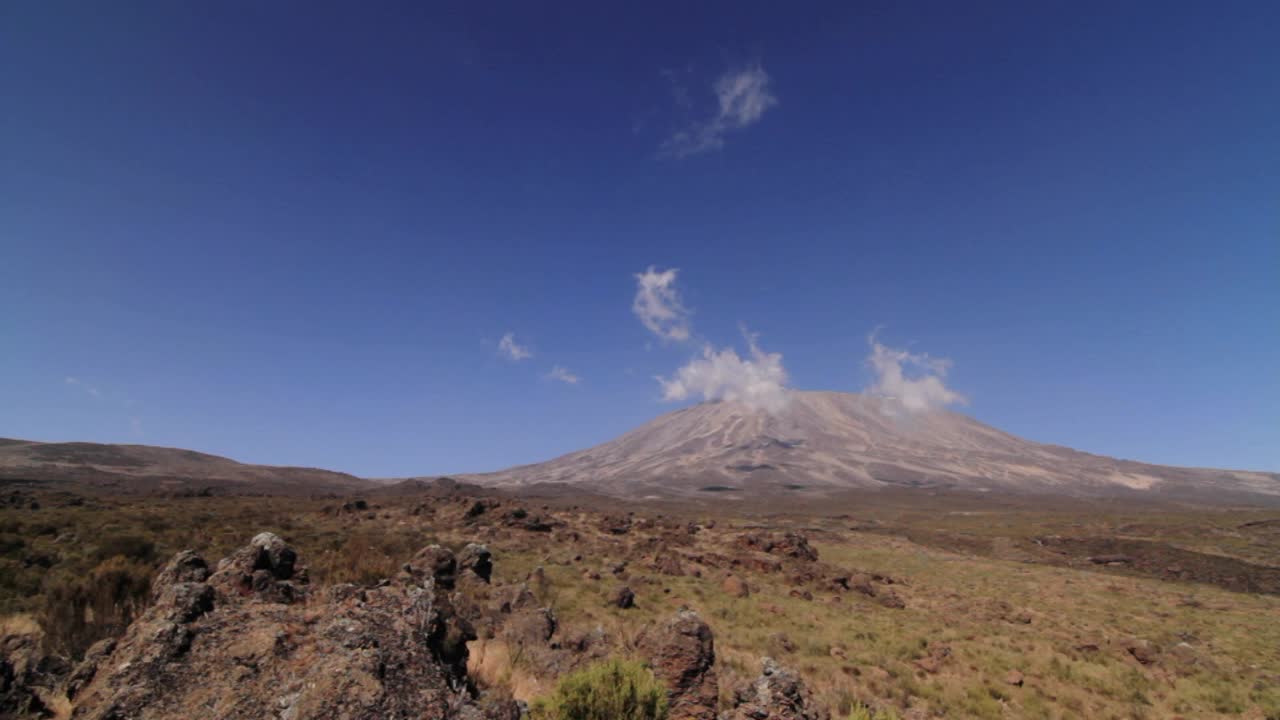 toma amplia del kilimanjaro con trekker caminando hacia el marco
