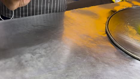 a street vendor skillfully prepares thai roti on a metal surface in phuket, showcasing traditional techniques and vibrant colors