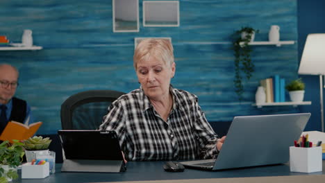 multitasking retired woman reading on laptop and tablet in same time