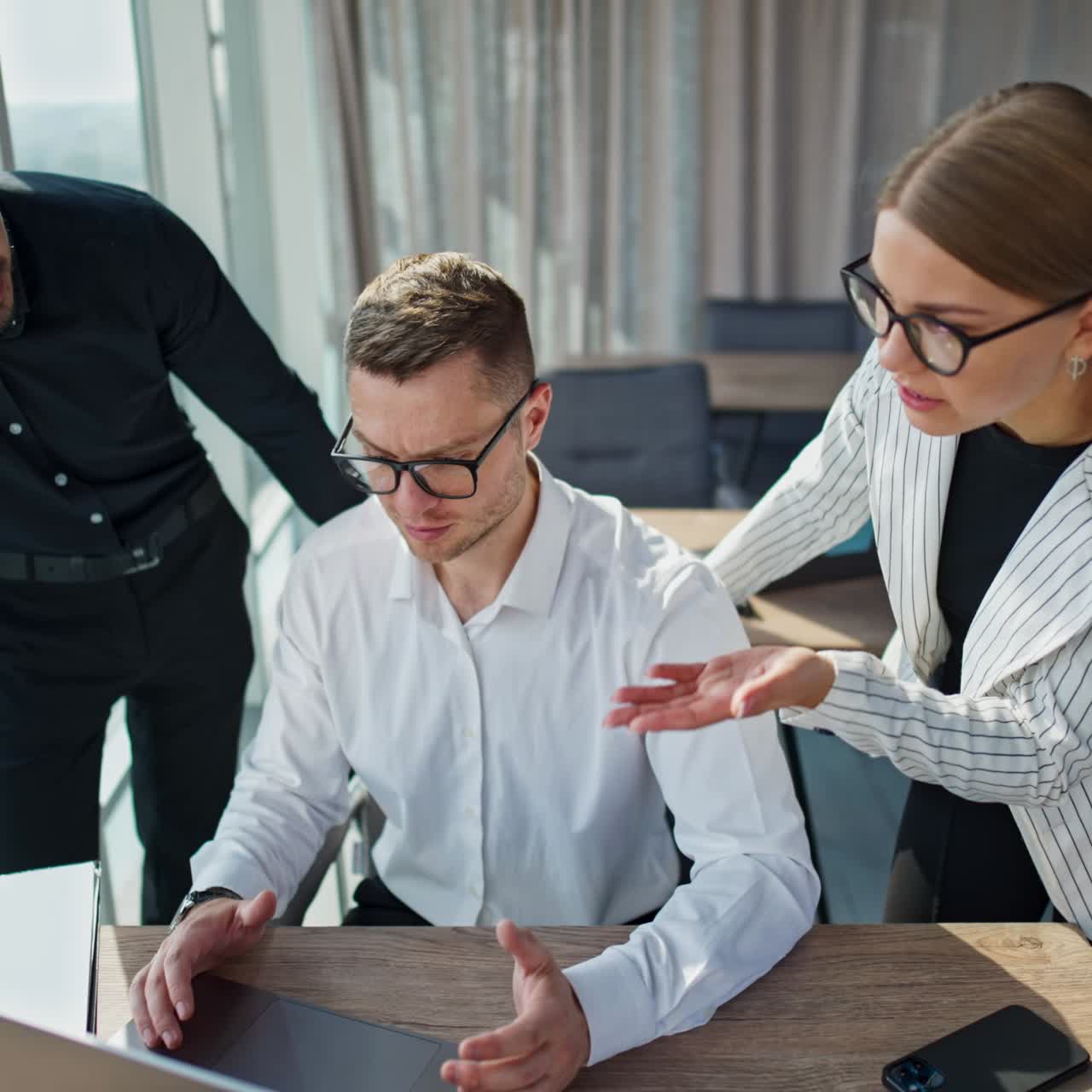 People cooperating at their work in office. Young teammates discussing something on laptop and laughing. Light office indoor backdrop