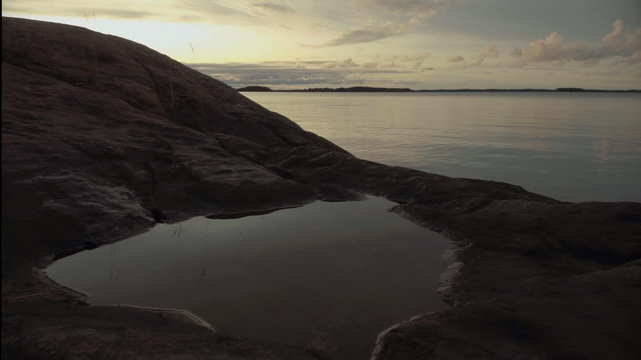lapso de tiempo de movimiento del acantilado de montaña con charco que se encuentra con el océano al atardecer, paso de barco