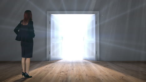 Door opening to light watched by businesswoman