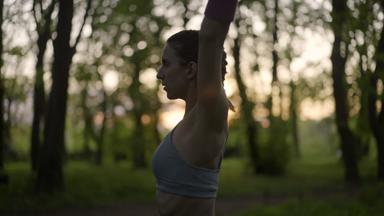 Woman stretching in a park at sunset