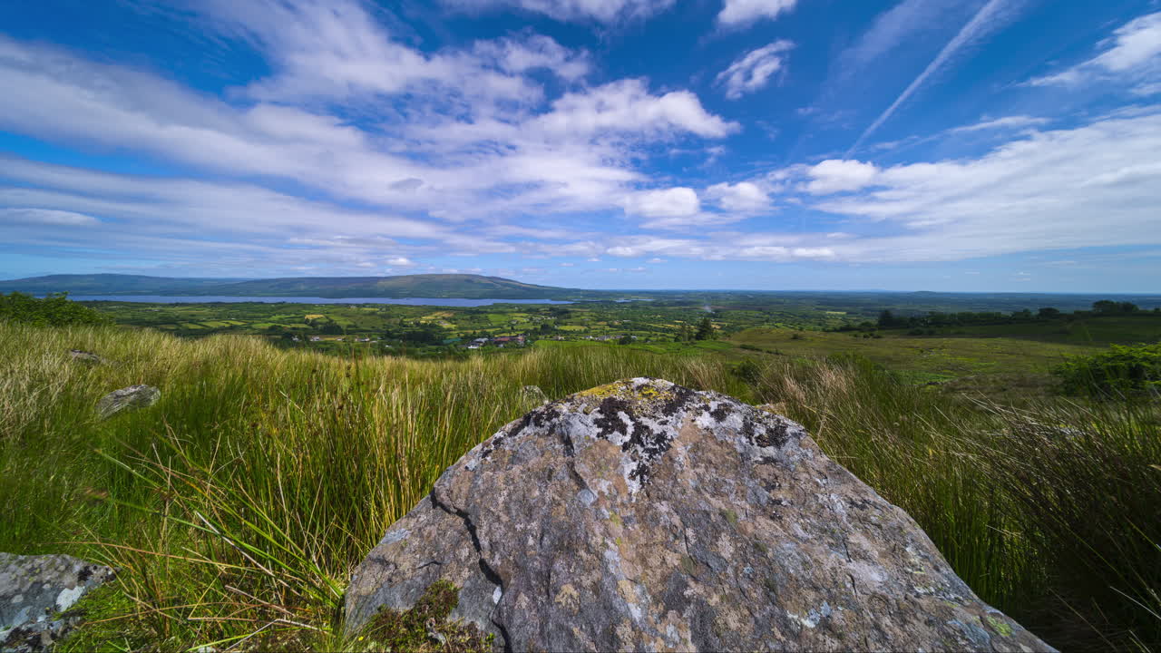 Motion time lapse of rural landscape with a single massive boulder rock in grassland hillside on a spring sunny day in Arigna mountains in county Leitrim in Ireland