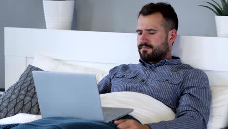 reacción de pérdida por un hombre triste usando una computadora portátil en la cama