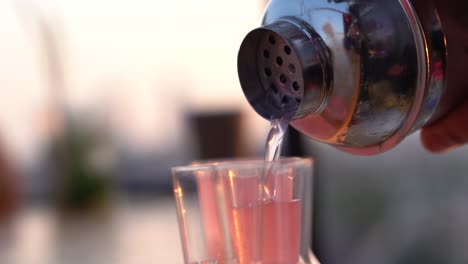 close-up of pouring shots in a line from a metal shaker