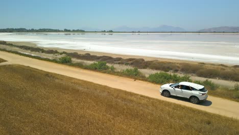 Aerial-View-of-Car-Passing-by-on-Salt-Pan-In-Igroviotopos-Alikis,-Kos,-Greece