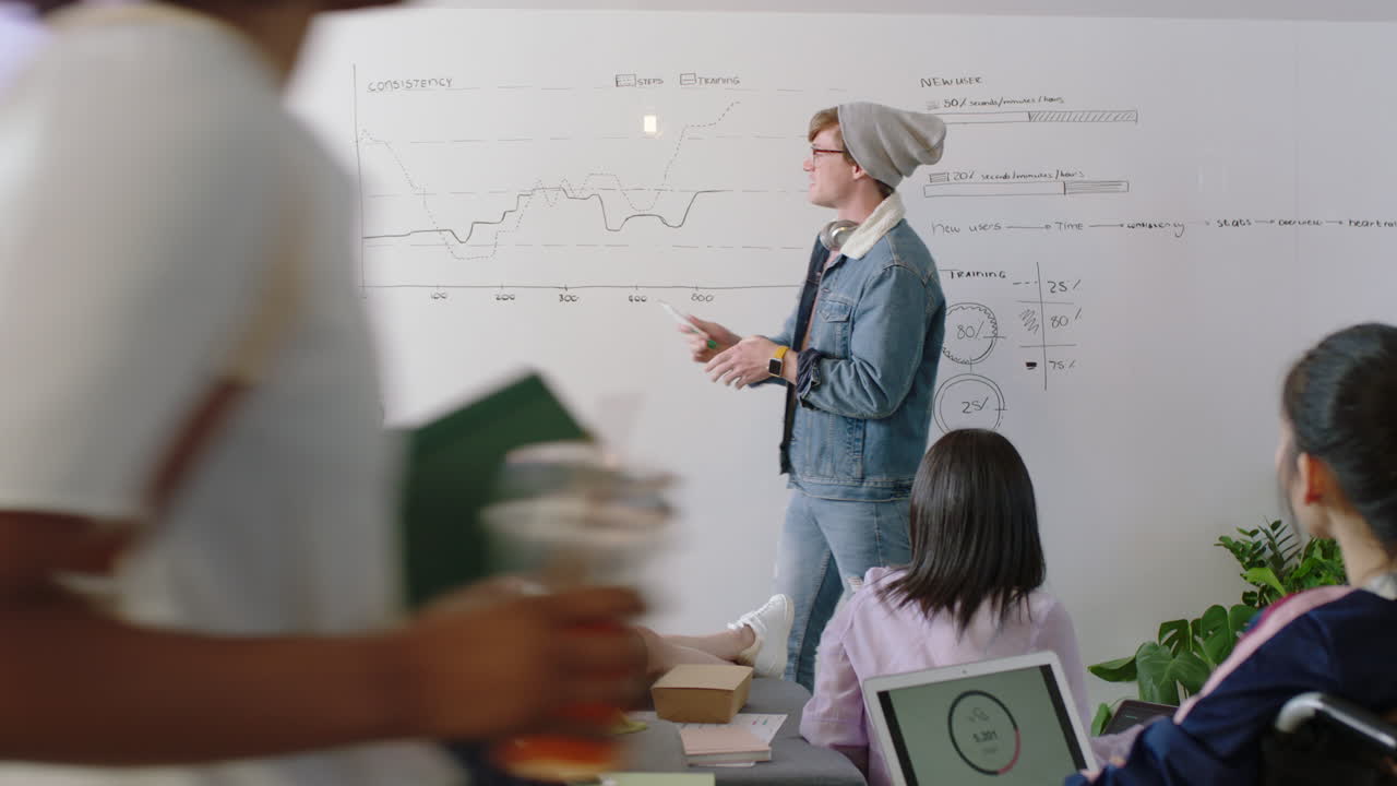 young caucasian man teaching group of students showing market statistics on whiteboard sharing graph data diverse team brainstorming creative ideas in office lecture