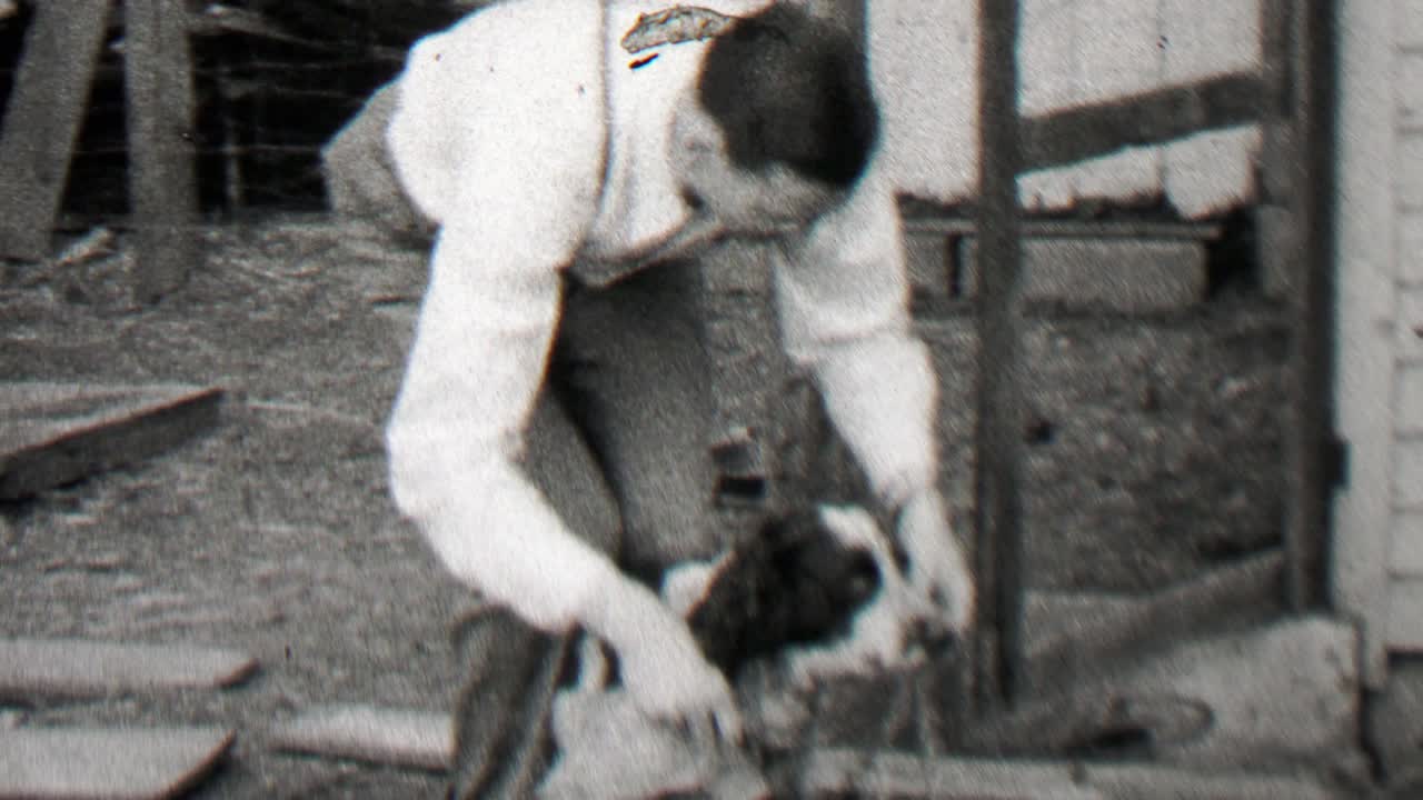 1938: un hombre elegante ajustando el collar de un perro de raza de caza sin idea.