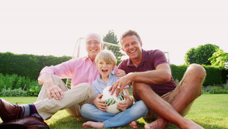 Abuelo,-Papá-E-Hijo-Sentados-En-El-Jardín-Con-Fútbol