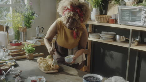 woman brushing freshly baked goods in a kitchen