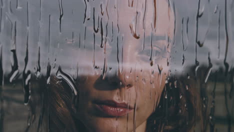 woman's face behind rain-streaked window