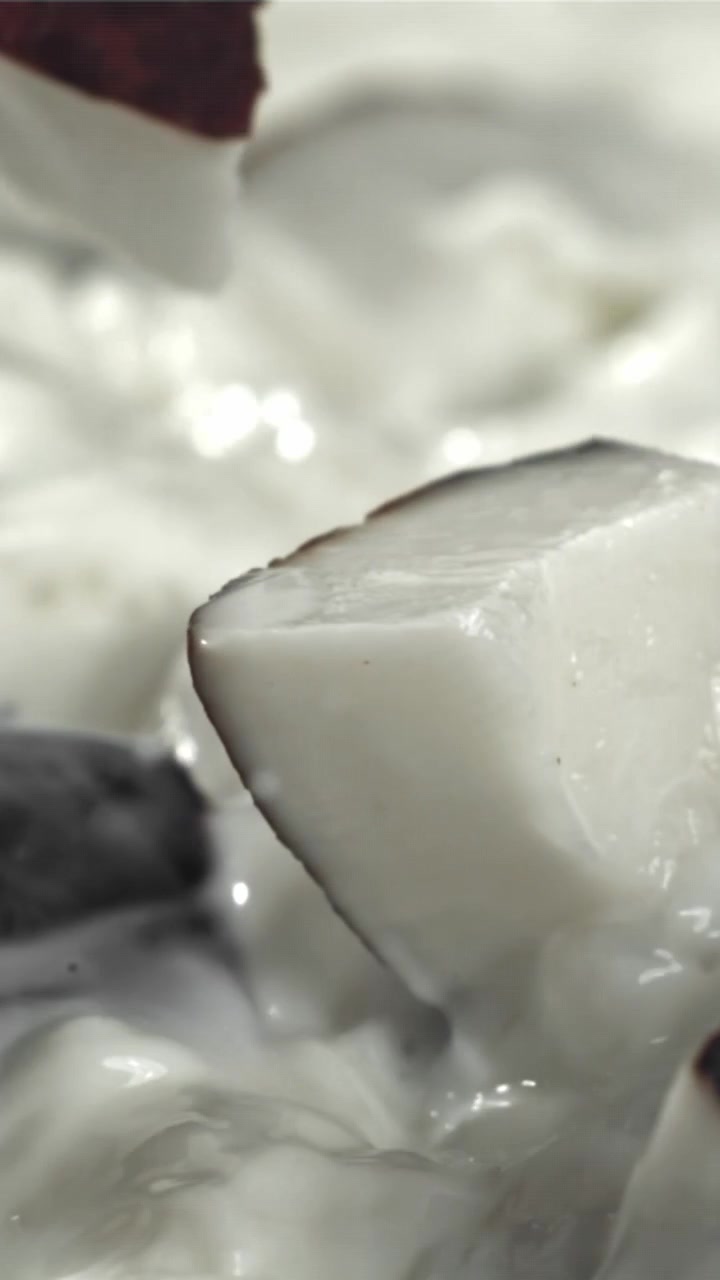 Movimento rallentato di pezzi di cocco che schizzano nel latte bianco