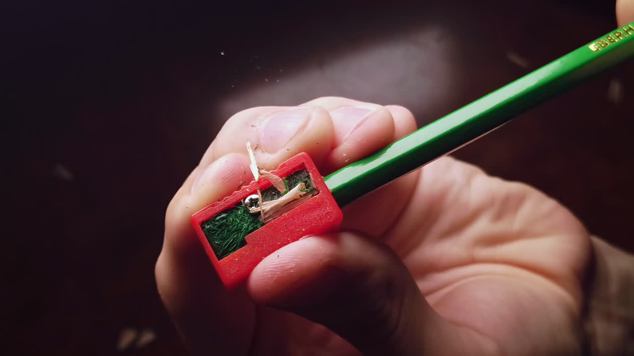 Overhead slow motion of sharpening the pencil in sharpeners on top of the wooden table