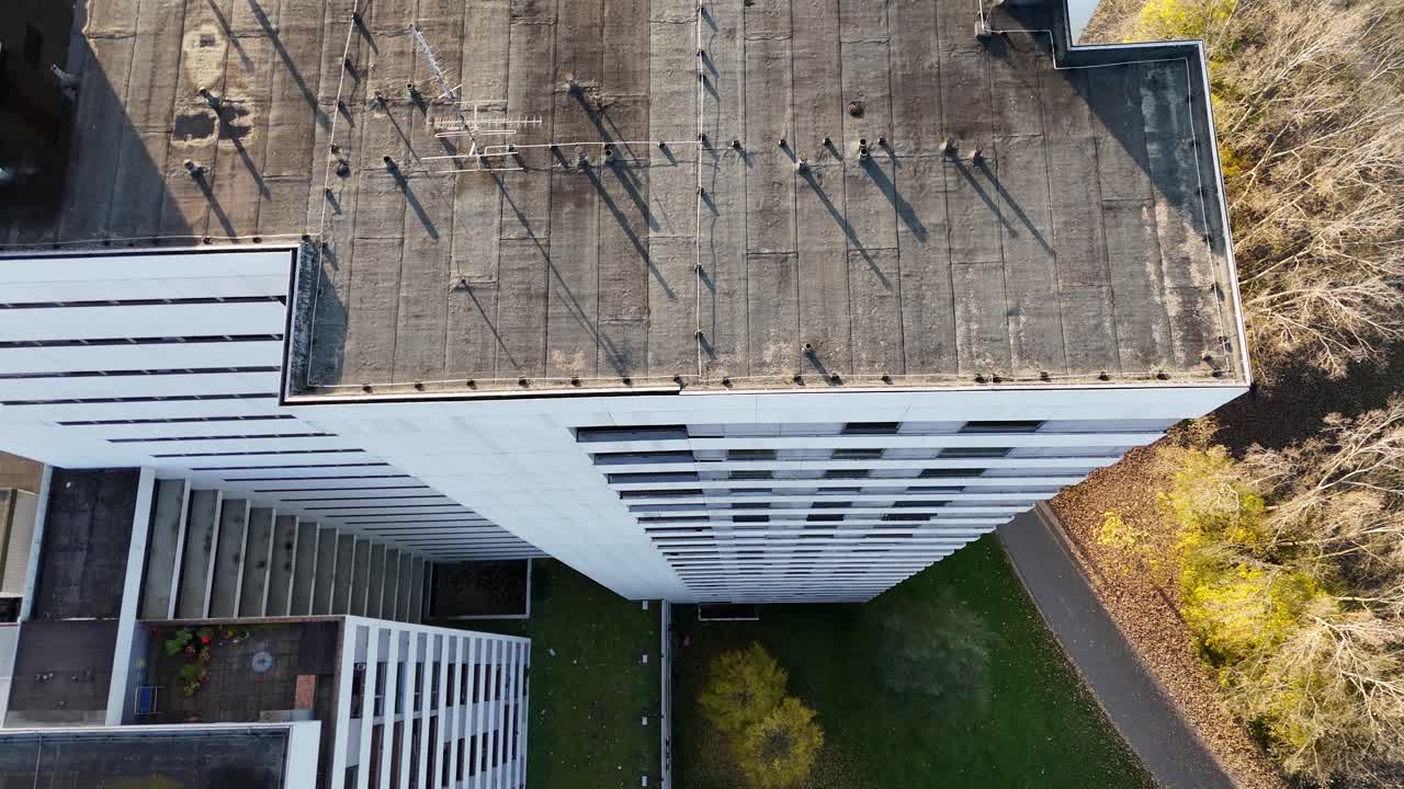 Un drone ruota attorno al bordo di un tetto rivelando alte torri residenziali circondate dal verde del parco