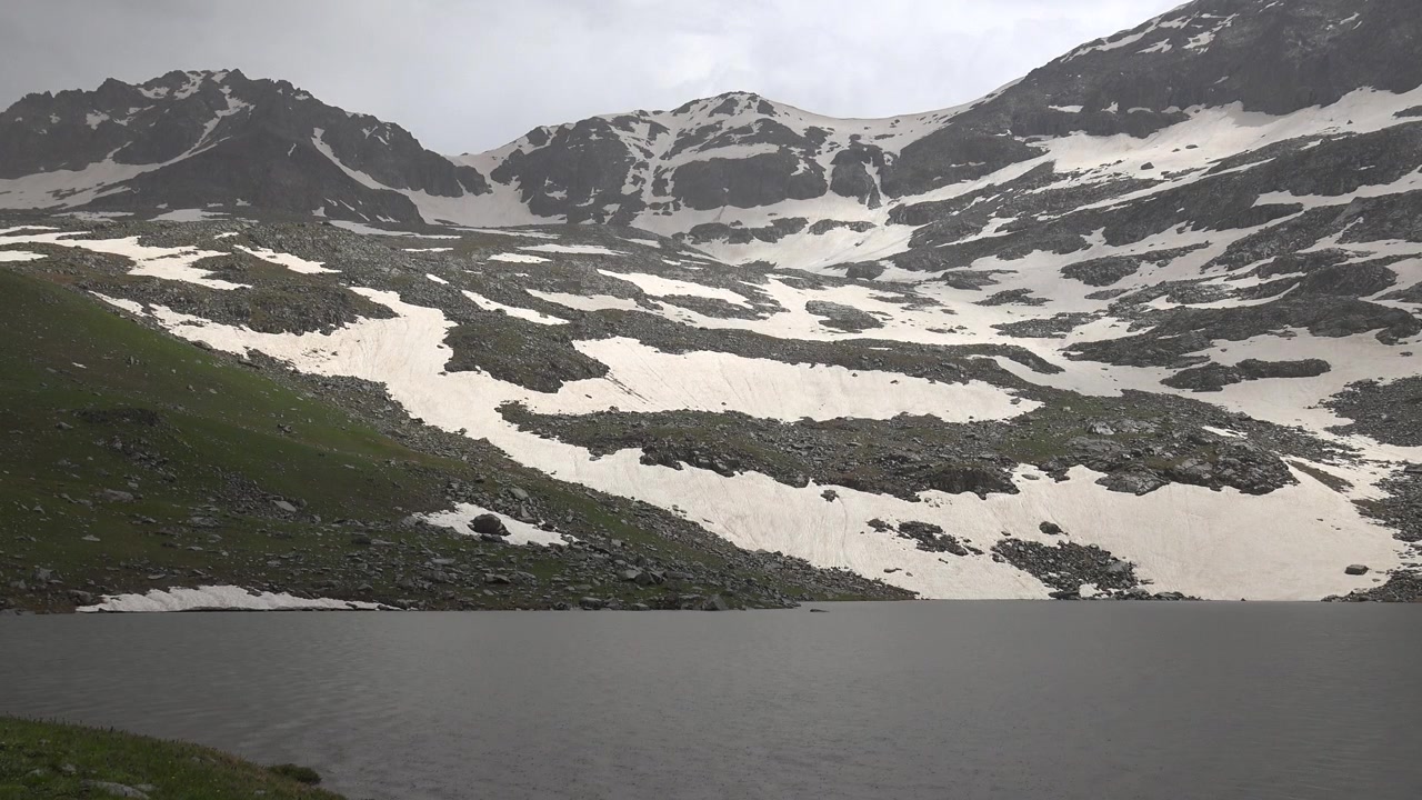 Snødekte fjelltopper som ruver over en rolig alpesjø