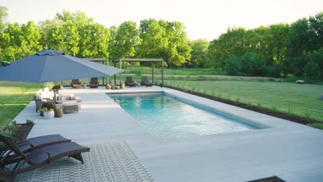 drone captures upscale backyard pool and twin pergolas in golden hour sunlight