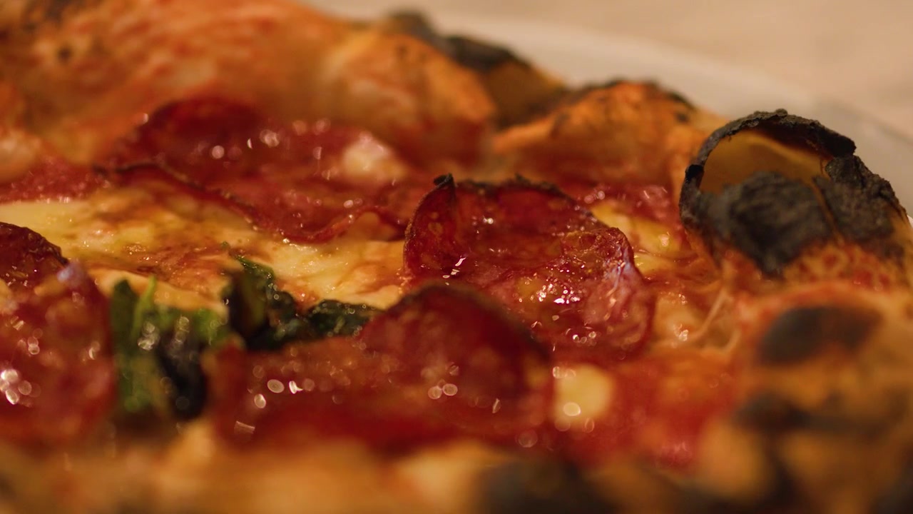 Primo piano di una pizza fresca al lievito madre con pepperoni che viene servita su un tavolo di marmo di un ristorante.