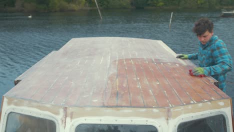 a carpenter wiping down sanded wheelhouse boat roof