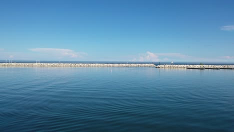 Toma-Aérea-Sobre-El-Agua-Mientras-Se-Acerca-A-Los-Rompeolas