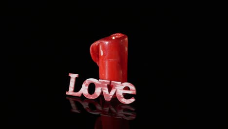 a single burning red candle rotate isolated in front of black background