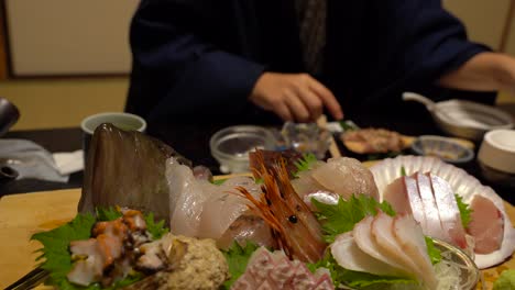 伝統的な日本の旅館の中の新鮮な魚介類と伝統的な服を着た女性の景色が背景にぼやけている