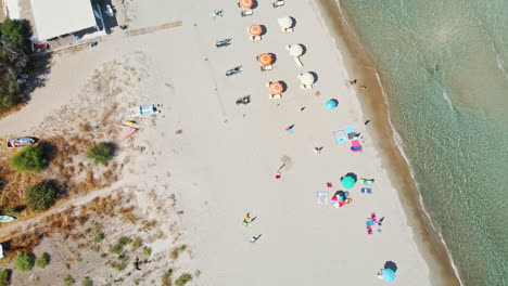 Bunte-Sonnenschirme-Am-Sommerstrand-Mit-Weißem-Sand-Mit-Menschen,-Die-Tropische-Kristallklare-Meereswellen-In-Sardinien,-Italien,-Genießen