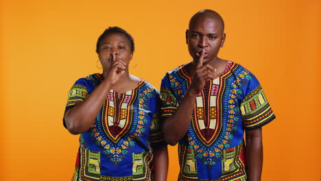 ethnic man and woman showing hush privacy sign