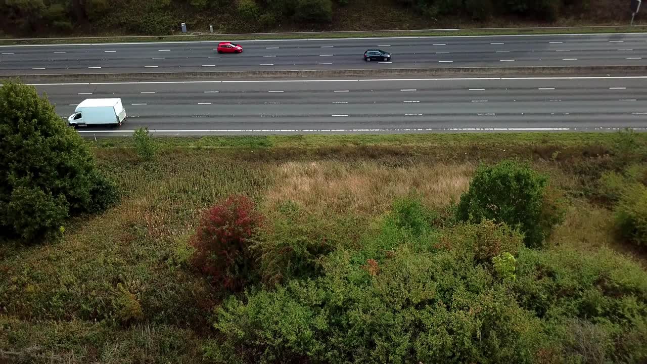 Drone reveak M1 Motorway with light traffic flying up from behind bushes