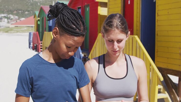 Multi-ethnic women using a phone on the beach and blue sky background