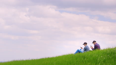 Zwei-Brüder-Im-Teenageralter-Sitzen-Auf-Einem-Malerischen-Grünen-Hügel