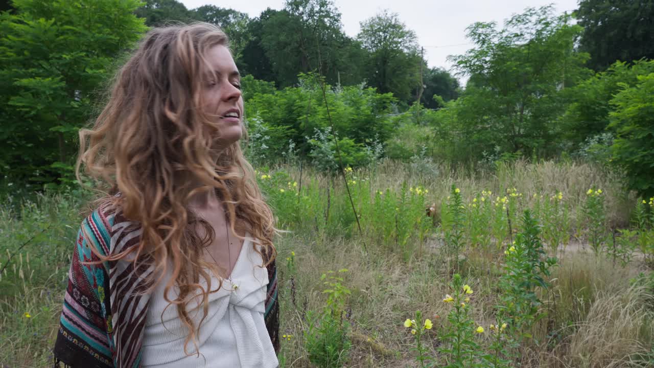 Happy young blonde hippie girl smiling at the camera in a rural country setting