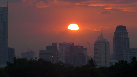 time lapse golden sunset behind clouds, city skyscrapers skyline in silhouette