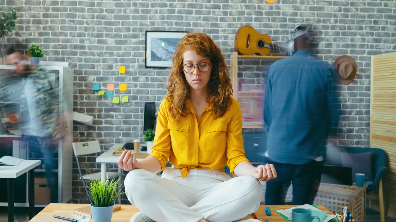 Woman meditating at her desk in a busy office