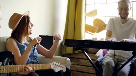 friends from musical band are playing musical instruments and singing, female vocalist is forgetting lyrics and laughing. friendship, music and fun concept.