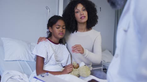 african american senior male doctor talking to african american mother and daughter at hospital