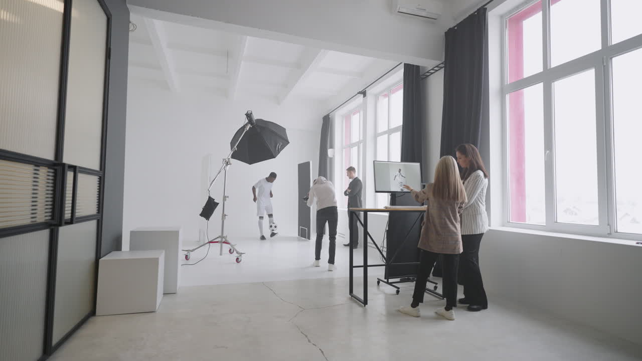 un equipo de fotografía profesional está filmando a un futbolista en el estudio. un jugador afroamericano está posando para la cámara.