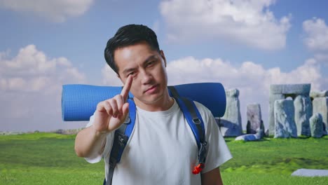 close up of asian male hiker with mountaineering backpack showing no gesture with index finger while traveling in stonehenge